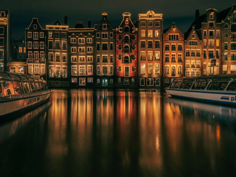 Canal houses in Amsterdam lit at night and reflected in the water