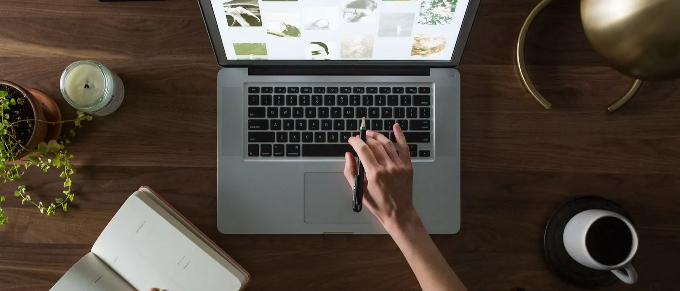 A laptop, notebook and coffee on a wooden desk
