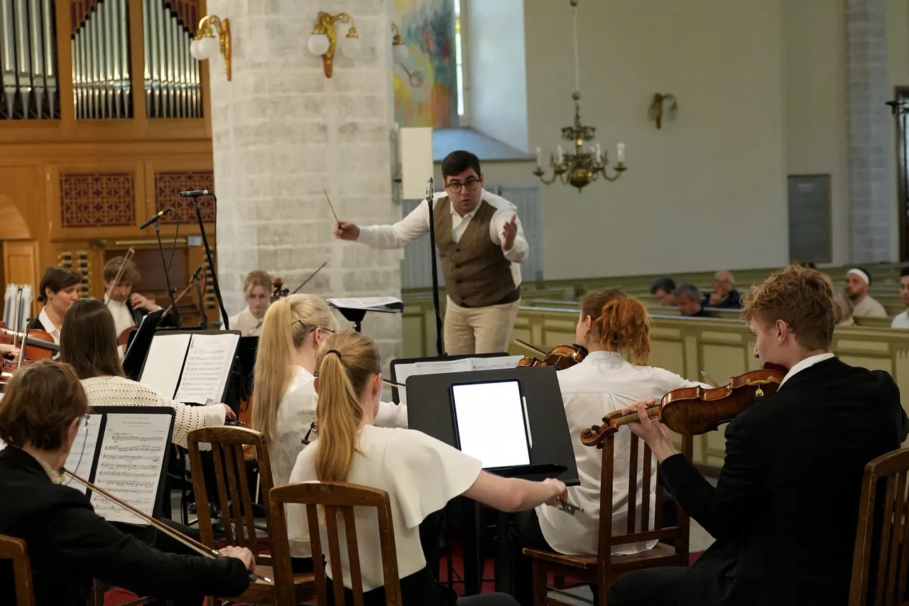 Eladio Aguilar conducting a string orchestra in a church, reaching towards the players