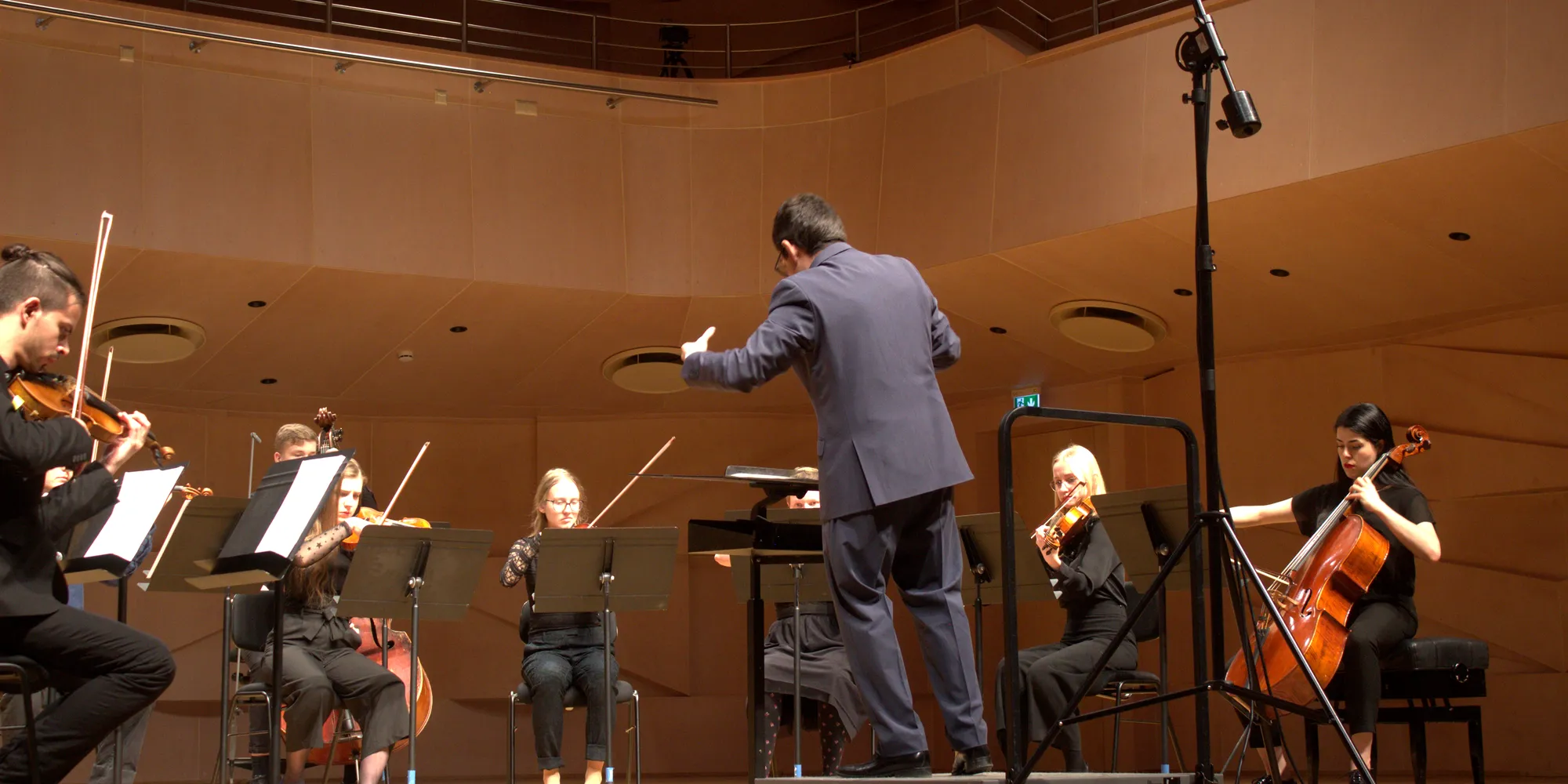 Eladio Aguilar conducting a string ensemble on a concert hall stage