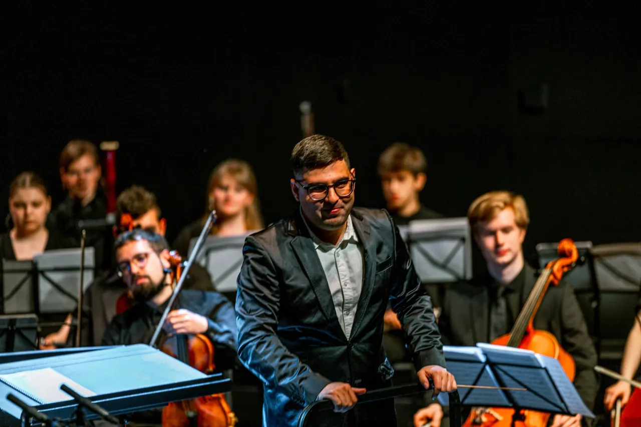 Eladio Aguilar on stage in front of the orchestra, smiling