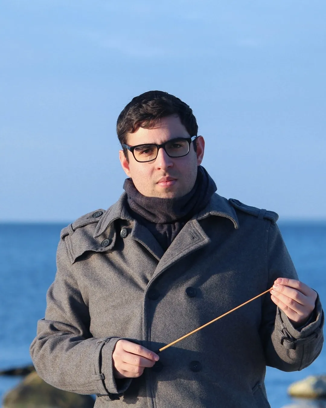 Eladio Aguilar holding a conductor&rsquo;s baton by the sea