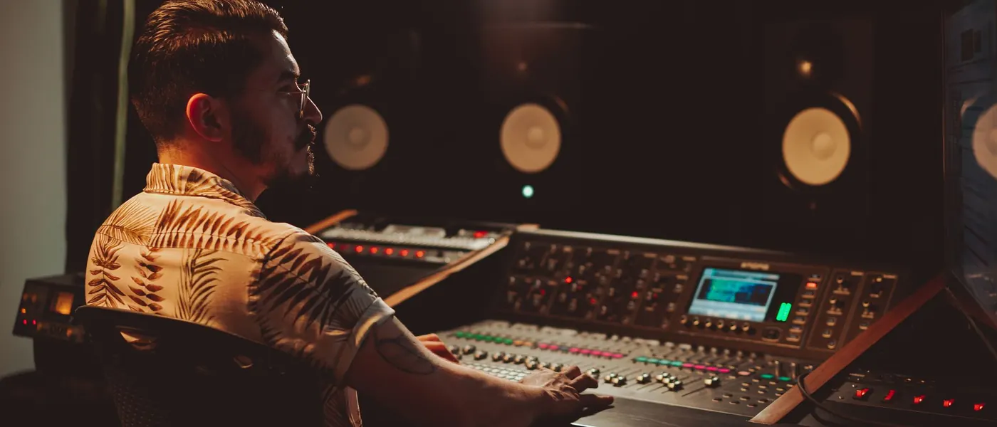 A producer at a mixing console in a dark studio