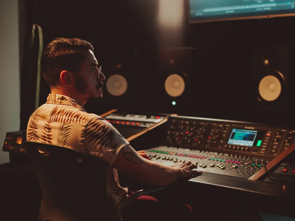 A producer working at a mixing console in a dimly lit studio
